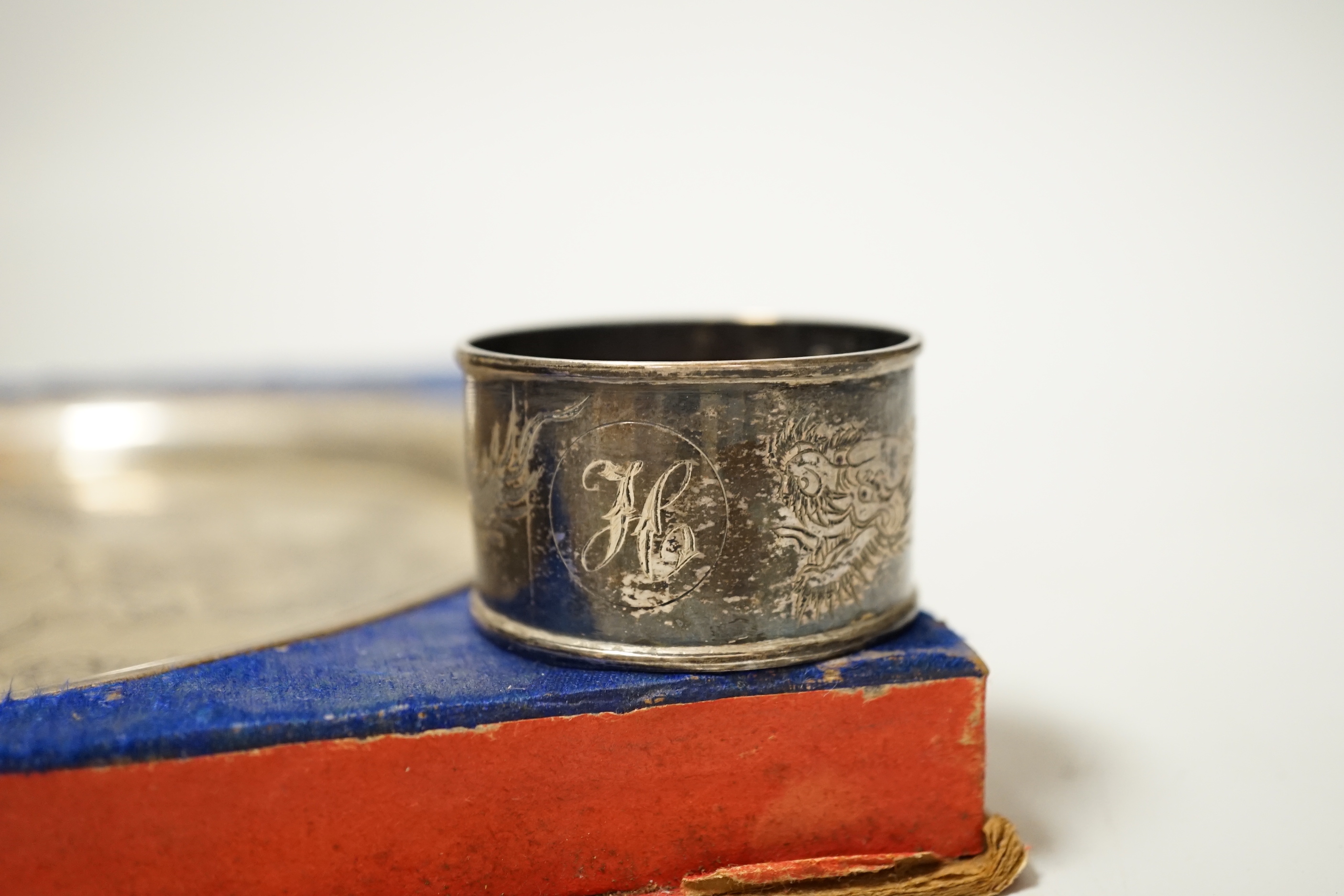 A Chinese white metal ‘dragon’ salver, late 19th century, 20.2cm carded silk box base and two similar napkin rings.